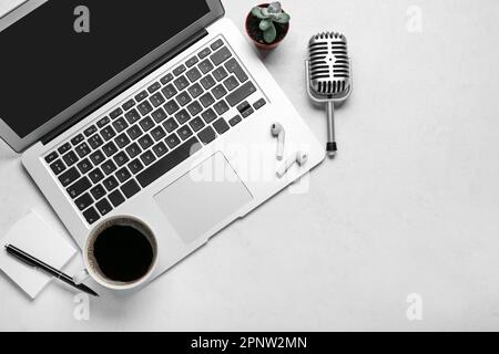 Ordinateur portable avec écouteurs, microphone, notes adhésives et tasse de café sur fond blanc Banque D'Images