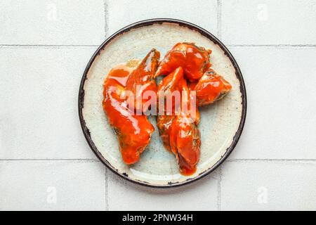 Assiette de poisson en conserve sauce tomate sur table carrelée de blanc Banque D'Images