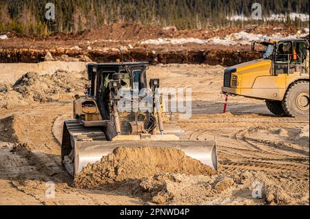 Bulldozer poussant du sable sur le fond d'une excavation dans la forêt boréale Banque D'Images