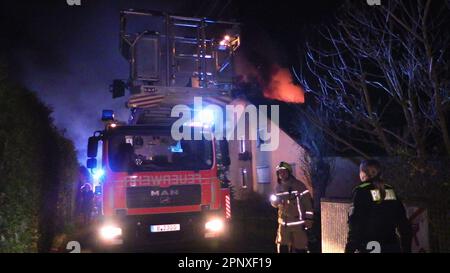 Berlin, Allemagne. 21st avril 2023. Un véhicule de service d'incendie se tient devant une maison en feu. Une maison mitoyenne a brûlé dans le quartier berlinois de Mahlsdorf. Comme l'a annoncé le service d'incendie vendredi, l'incendie a éclaté tôt vendredi matin à Pfingstweg dans le quartier de Marzahn-Hellersdorf. Selon le rapport, les flammes se sont répandues sur deux étages. Un résident s'est rendu en sécurité et a été transporté à l'hôpital avec suspicion d'inhalation de fumée. Credit: Dominik Totaro/dpa/Alay Live News Banque D'Images