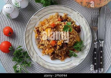 Bœuf avec boulgour et légumes tels que la citrouille, les carottes, les oignons et les tomates séchées au soleil, vue de dessus Banque D'Images