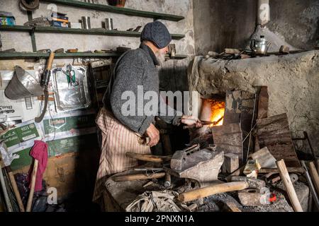 Forgeron traditionnel travaillant dans la forge de son atelier. Banque D'Images