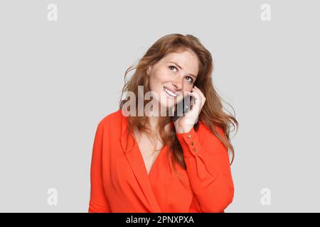 Parfaite femme souriante et rouge parlant au téléphone sur fond blanc Banque D'Images