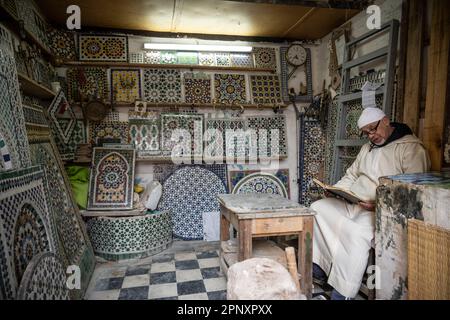 Artisan lisant un livre en attendant qu'un client arrive à sa boutique de mosaïque. Banque D'Images