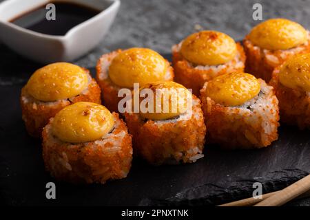 Ensemble de rouleaux de sushis frais. Les sushis roulent la californie avec du fromage. Sushi sur fond noir, baguettes, wasabi, soya. Vue de dessus. Banque D'Images