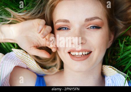 Jeune femme blonde insouciante, couchée dans l'herbe et profitant de l'été Banque D'Images