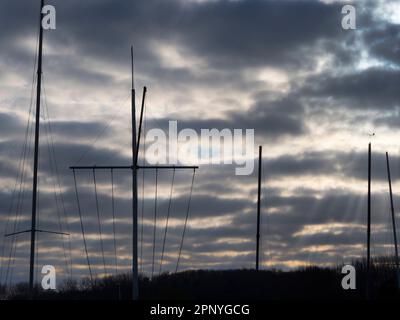 Ciel couvert sombre et luisant, gamme abstraite de mâts de yachts et de gréement au lever du soleil à Abingdon Marina près de la Tamise. Banque D'Images