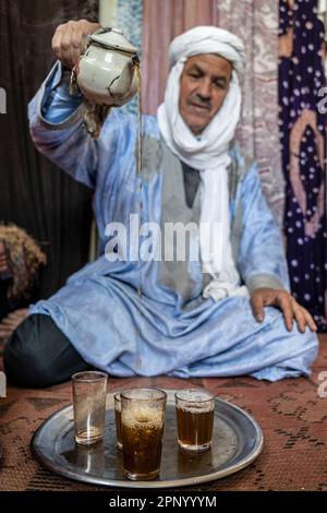 Touareg faisant du thé assis sur le sol sur un tapis. Banque D'Images