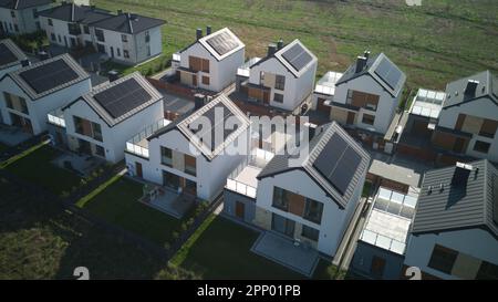 Vue aérienne du printemps des maisons communautaires chaudes et ensoleillées de quartier avec rue unique et champ autour. Banque D'Images