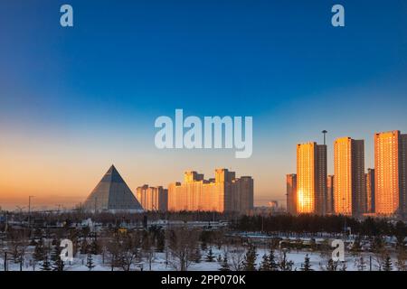 Astana, Kazakhstan - 2 février 2023 : coucher de soleil en soirée paysage urbain avec le Palais de la paix et de la réconciliation emblématique de Norman Foster Banque D'Images