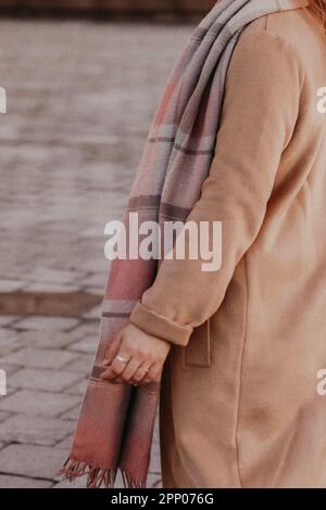 Femme portant un manteau chaud beige long automne et une écharpe confortable à carreaux. Portrait de mode en plein air Banque D'Images