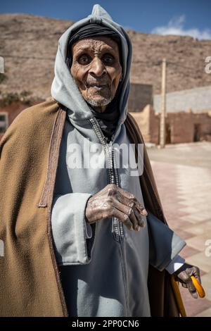 Portrait d'un vieil homme habillé de vêtements traditionnels, penché sur une canne. Banque D'Images