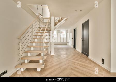 une chambre vide avec des escaliers et du parquet dans la partie centrale de la chambre il y a une porte noire sur le côté droit Banque D'Images