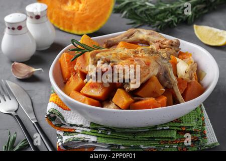 Viande de lapin à la citrouille et à l'ail dans une assiette légère sur fond gris Banque D'Images