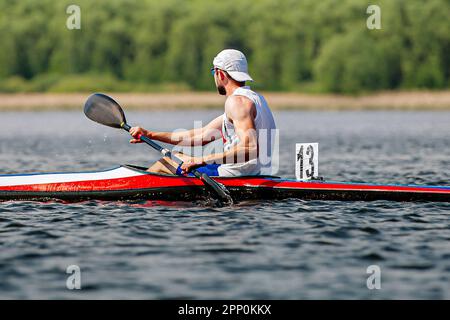 vue latérale mâle athlète de kayakiste en kayak simple dans la course de championnat de kayak, bateau numéro 13 Banque D'Images