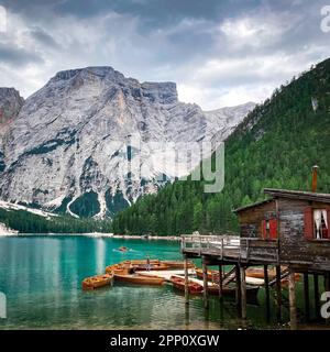 Un paysage côtier pittoresque avec plusieurs petits bateaux en bois amarrés sur la rive avec une montagne majestueuse en arrière-plan Banque D'Images