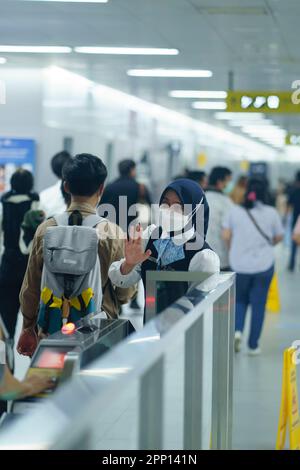 Une femme sympathique saluant les passagers à la porte d'entrée de la station MRT, Jakarta. Indonésie. 20 avril 2023. Banque D'Images