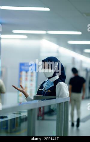 Une femme sympathique saluant les passagers à la porte d'entrée de la station MRT, Jakarta. Indonésie. 20 avril 2023. Banque D'Images