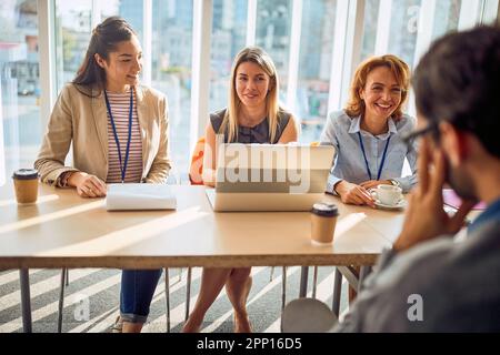 Un groupe de jeunes femmes d'affaires dans une commission profite d'une entrevue dans une atmosphère agréable avec un beau candidat masculin pour un poste Banque D'Images