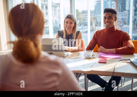 Jeunes collègues d'une commission ayant une conversation agréable avec une jeune candidate dans une atmosphère détendue lors d'une entrevue d'emploi. Entreprise, Banque D'Images
