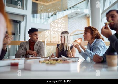 Les jeunes gens d'affaires discutent et apprécient de manger une pizza pendant une pause déjeuner dans une atmosphère amicale dans le bâtiment de l'entreprise. Affaires, personnes, c Banque D'Images
