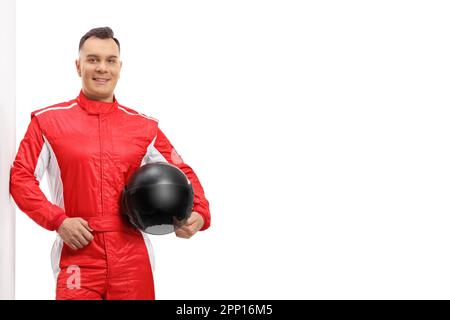 Racer dans un costume rouge appuyé sur un mur et tenant un casque noir isolé sur fond blanc Banque D'Images