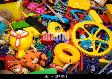 Une abondance de jouets dans la chambre des enfants, beaucoup de pièces en plastique multicolores de designers, pièces de rechange pour jouets, figurines et cubes. Banque D'Images