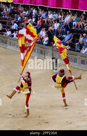 Sienne, Italie - 17 août 2022: Jeux de drapeaux avec porteur drapeau agitant et lançant drapeau du Contrade Valdimontone au Palio di Siena Corteo Stor Banque D'Images