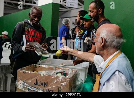 21 avril 2023, Brésil, São Paulo: Un homme montre un livre au prêtre Julio Lancellotti (r) comme il distribue de la nourriture aux gens. Lancellotti est connu dans le pays sud-américain pour son travail en faveur des droits de l'homme et des classes les plus pauvres. Grâce à des dons, il fournit aux gens de la nourriture, des vêtements et des livres. Il s'oppose également à ce qu'il appelle « l'hostilité envers les pauvres ». Photo : Allison Sales/dpa Banque D'Images