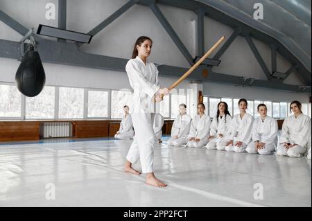 Jeune fille luttant avec une épée en bois à l'entraînement d'aikido dans l'école d'arts martiaux Banque D'Images