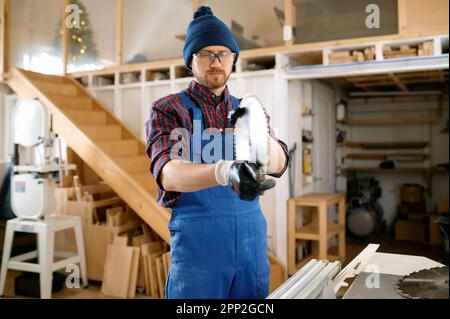 Homme charpentier préparant une lame de scie ronde pour le travail du bois à l'atelier Banque D'Images