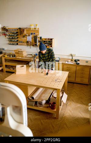 Menuisier de l'homme faisant le dessin technique avec un crayon sur panneau de bois Banque D'Images