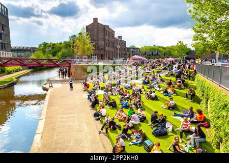 Personnes assises sur les marches de Granary Square surplombant Regent's Canal, King's Cross, Londres, Angleterre, Royaume-Uni Banque D'Images