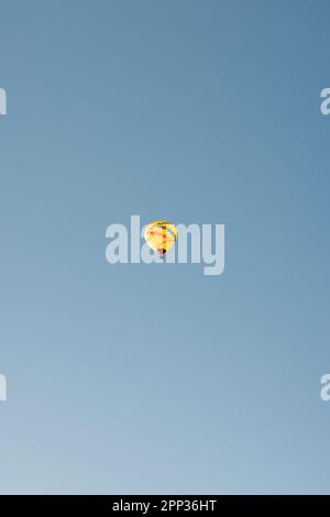 Vue à angle bas d'un ballon d'air chaud jaune à Sedona Arizona isolé sur fond bleu ciel en début de matinée. Banque D'Images