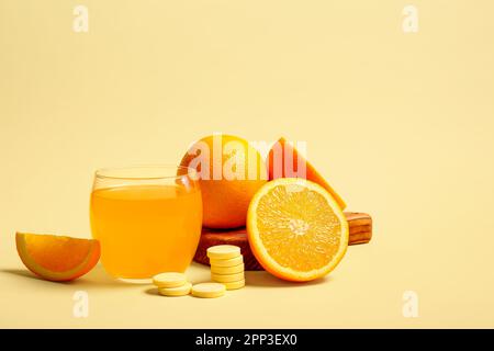 Conseil avec un verre de comprimé effervescent de vitamine C dissous dans l'eau et des oranges sur fond beige Banque D'Images