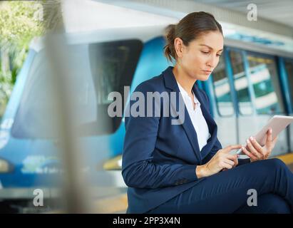 Travail et déplacements. femme d'affaires utilisant une tablette numérique en attendant un arrêt de transport en commun. Banque D'Images