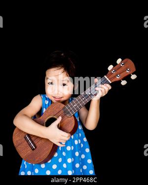 Un petit enfant asiatique joue le ukulele Banque D'Images