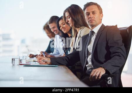 Peu importe votre expérience, apprenez toujours plus. Portrait d'un homme d'affaires lors d'une réunion avec ses collègues en arrière-plan. Banque D'Images