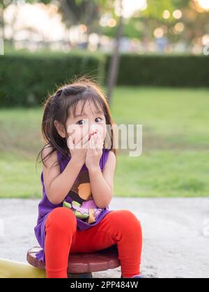 Petite fille asiatique couvrant sa bouche avec ses mains. Surpris ou peur. Banque D'Images