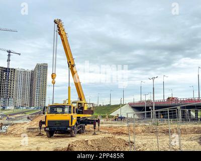 les machines de construction construise une grande zone résidentielle. construction de maisons à partir de blocs, verre. un camion lourd jaune soulève des dalles de béton lourd pour h Banque D'Images