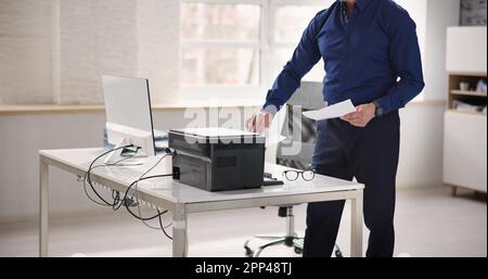 Homme utilisant une machine à photocopier dans Office. Imprimante et copieur Banque D'Images