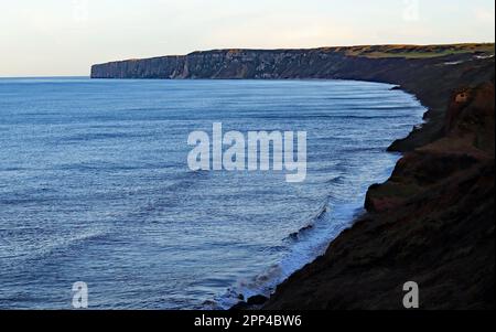 Hunmanby Sands, et Hunmanby Bay lors d'une soirée de printemps avec la marée et le soleil bas mettant en évidence les sommets de la falaise tandis que la mer est un bleu pâle ombre Banque D'Images