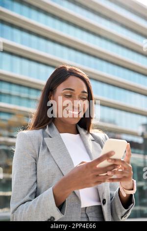 Portrait vertical d'une femme d'affaires afro-américaine tenant un smartphone. Banque D'Images
