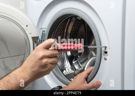 Jeune plombier fixing lave-linge dans la salle de bains, gros plan Banque D'Images