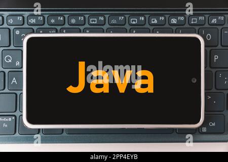Java langage de programmation pour le développement mobile, concept. Smartphone sur le clavier de l'ordinateur portable, le poste de travail du programmeur. inscription java sur le mobile Banque D'Images