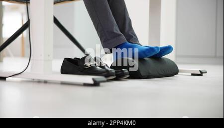 Homme utilisant un repose-pied pour réduire la tension du dos et la fatigue des pieds Banque D'Images