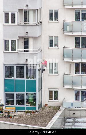 un homme de nettoyage de fenêtre suspendu sur des cordes bâtiment résidentiel travaillant avec le visage non visible Banque D'Images