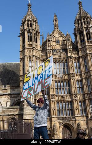 Londres, Royaume-Uni -22.04.2023, The Big One Demonstration. Homme tenant une affiche - mettre fin à la criminalité climatique sur fond de Parlement Banque D'Images