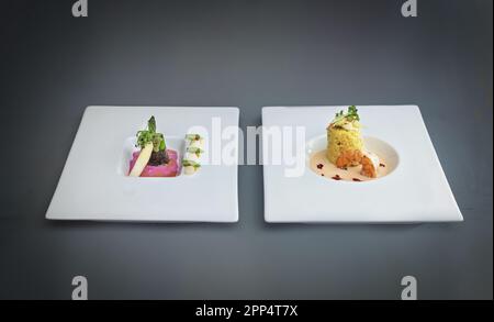 Deux plats d'un menu gastronomique moderne, asperges en feuilles de nori avec sauce aux betteraves, plat de poisson de risotto au safran avec sauce aux crevettes et aux crustacés, gra Banque D'Images