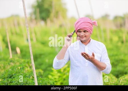 Jeune agriculteur indien montrant Smart phone, agriculteur parlant au téléphone dans la ferme, heureux agriculteur indien Banque D'Images